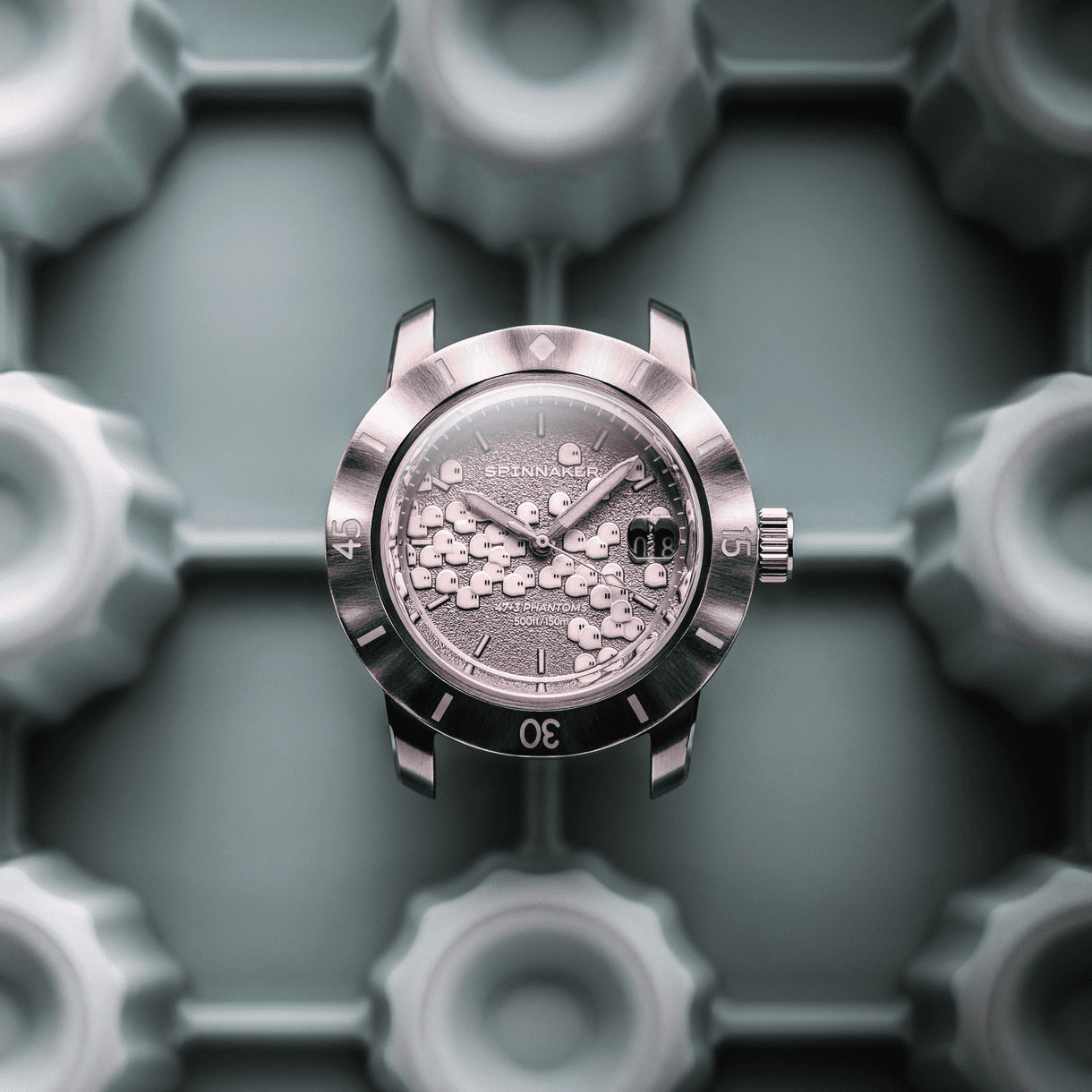 スピニカー（SPINNAKER）と、パリの気鋭アーティスト ロマリック・アンドレ率いる seconde/seconde/（セコンド／セコンド）による最新コラボレーションモデル「FLEUSS AUTOMATIC SECONDE/SECONDE/ 2025 EDITION（SP-5170-11B）」。幽玄な“ファントム”の世界をテーマに、スペクトラル・グレーのダイヤル上を47体＋3体の亡霊が行進する幻想的なデザインが特徴です。立体的なモールドによって造形されたファントムたちは、暗所でホワイト・ブルー・グリーンの3色のスイスルミナスが妖しく光り、まるで現世と常世をつなぐかのような独特の存在感を放ちます。裏蓋のシースルーバックからは日本製自動巻ムーブメントの精緻な動きと、幽霊の姿をしたローター装飾が覗き、遊び心とクラフトマンシップが融合。波打つベゼル、ライスブレスレット、そして蓄光仕様のナイロンストラップを備えた特別仕様です。世界限定1,150本の初回生産「2025 Edition Batch No.1」として登場する本作は、時計アートの枠を超えたコレクターズピース。異彩を放つ美学を手首に宿す、ファントムたちの行進を
