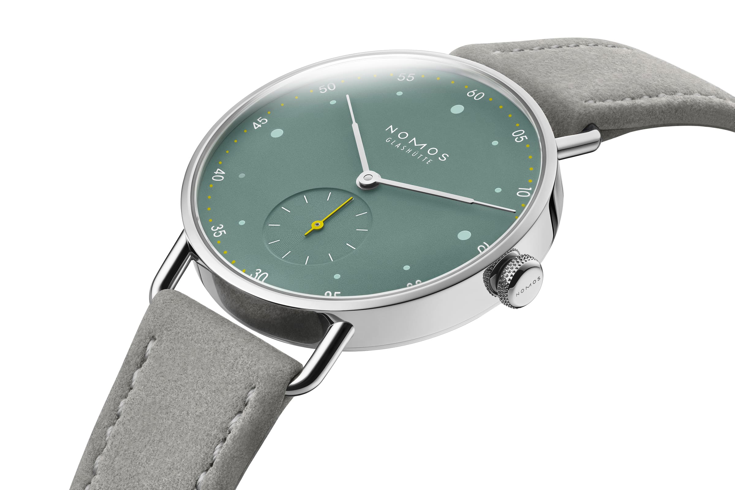 NOMOS Glashütte / METRO 33 / NM1124スタイリッシュなメトロの10周年に向けて、フェミニンなサイズ33のSSケースがファミリーに加わります。  大都会をイメージしたメトロ33は輝くガラス張りのビル（オールシルバー）・ブルックリンによくみられる赤煉瓦の建物（ミュートレッド）・公園や自由の女神の心豊かな緑（セージ）の3色です。  複雑なダブルカーブのサファイアクリスタルガラス、繊細なワイヤーラグ、また時計師が使う道具をモチーフにした特徴的なメトロリューズなど、すべてが非の打ちどころのないグラスヒュッテのクラフツマンシップと最高基準のデザインです。  時計のデザインを引き締めているのはライトグレーのヴィーガンベロアストラップ。スマートで遊び心があり、エネルギーに満ちている現代的なエレガンスを表現している3種類のメトロは、女性でだけでなくもちろんスレンダーな腕周りの男性にも似合います。